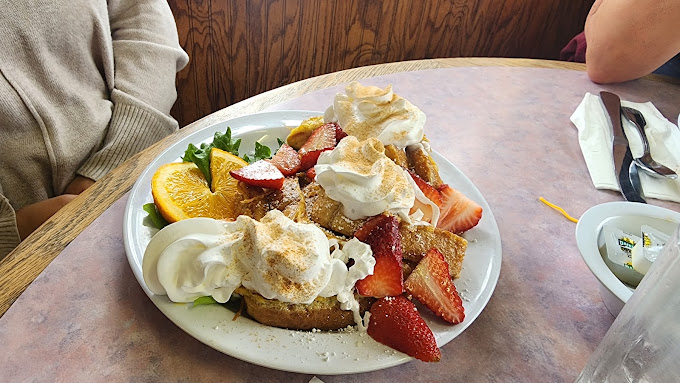 Stuffed French toast piled with whipped cream, strawberries and powdered sugar at Sugar Shack Cafe