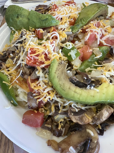 Hash browns topped with avocado, mushrooms, tomato, peppers and melted cheese at Sugar Shack Cafe